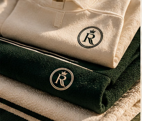 Folded ivory and green apparel with the crowned R emblem