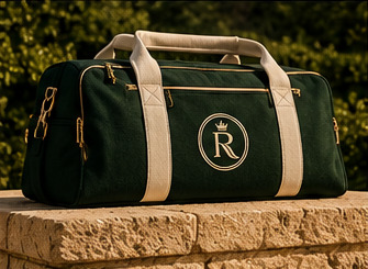 Forest-green duffel bag with ivory handles resting on stone